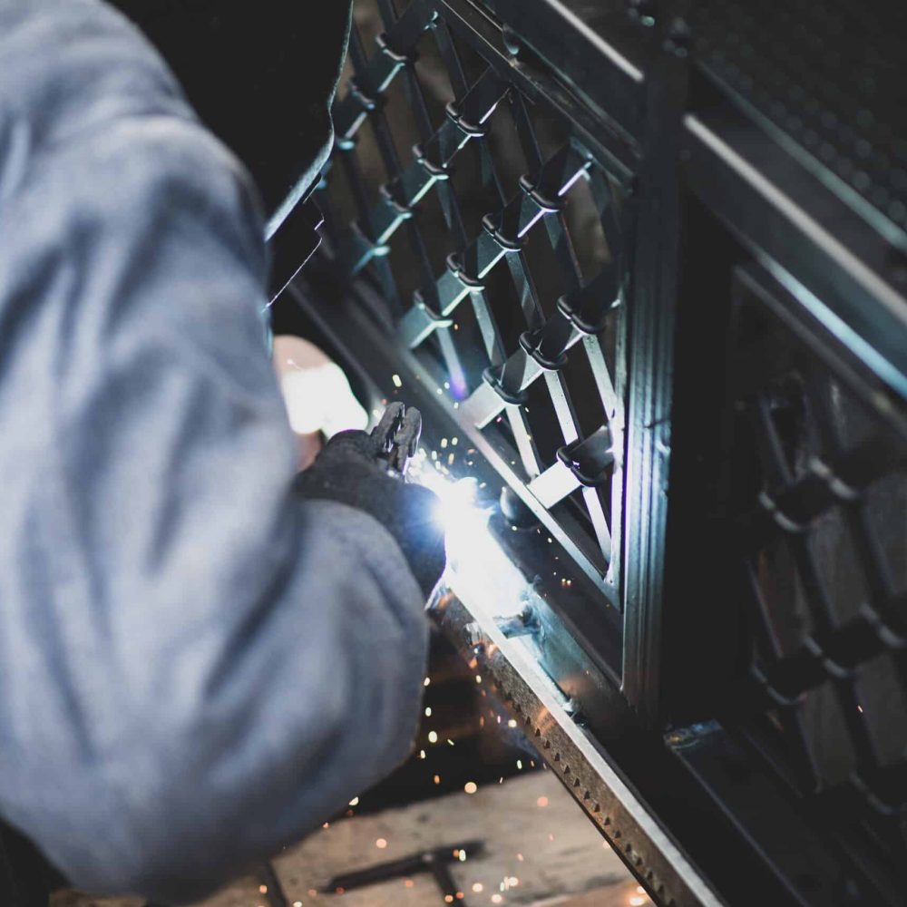 Welder welds the steel gear racks to gate before setting up automated gate operator. Professional service of installation and maintenance of automatic cantilever sliding gate